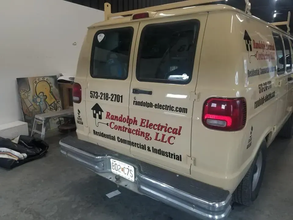Tan Randolph Electrical van, parked indoors. Includes phone number, website, and business services details.