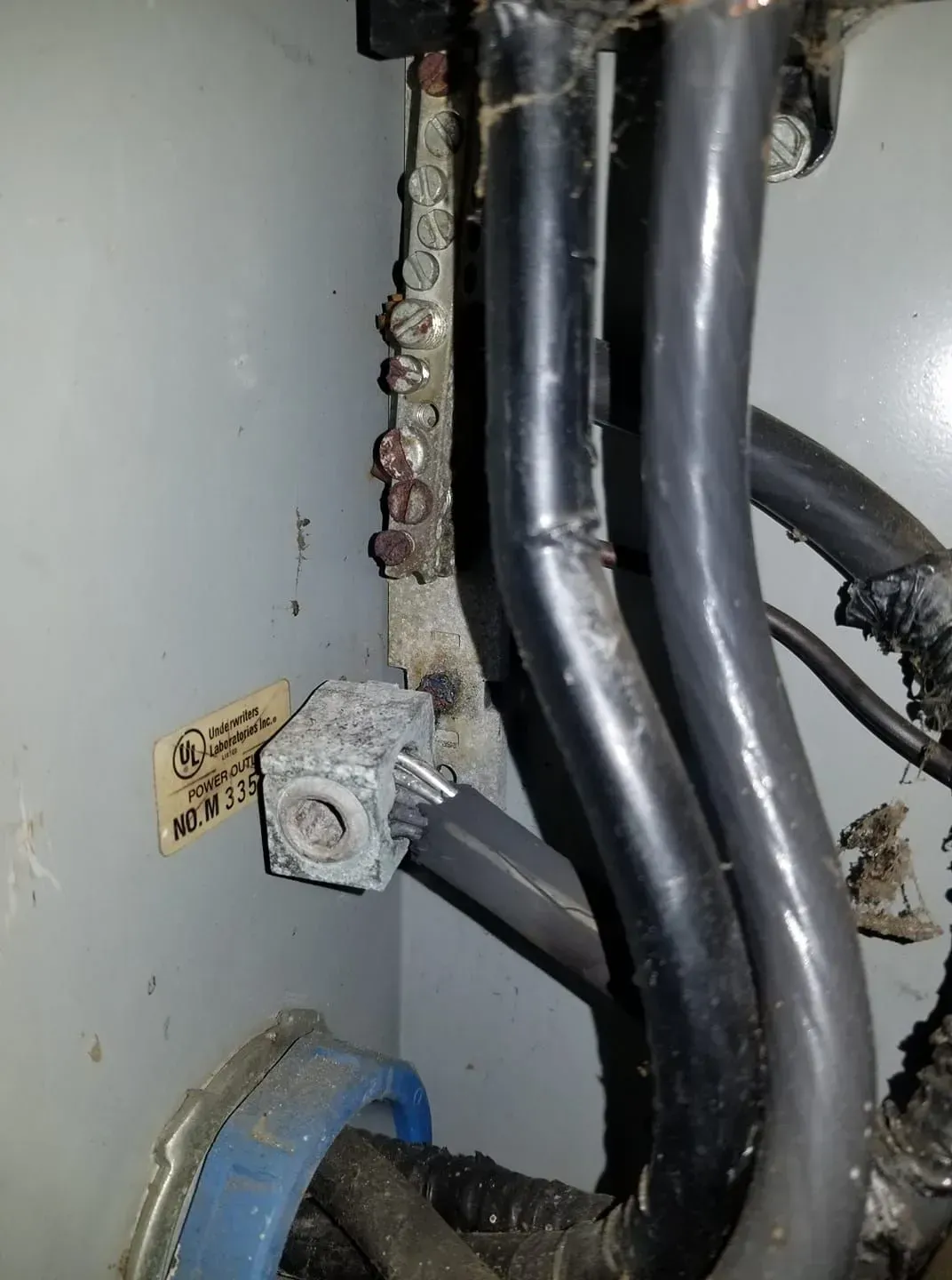 Damaged electrical panel with corroded grounding hardware and wires.