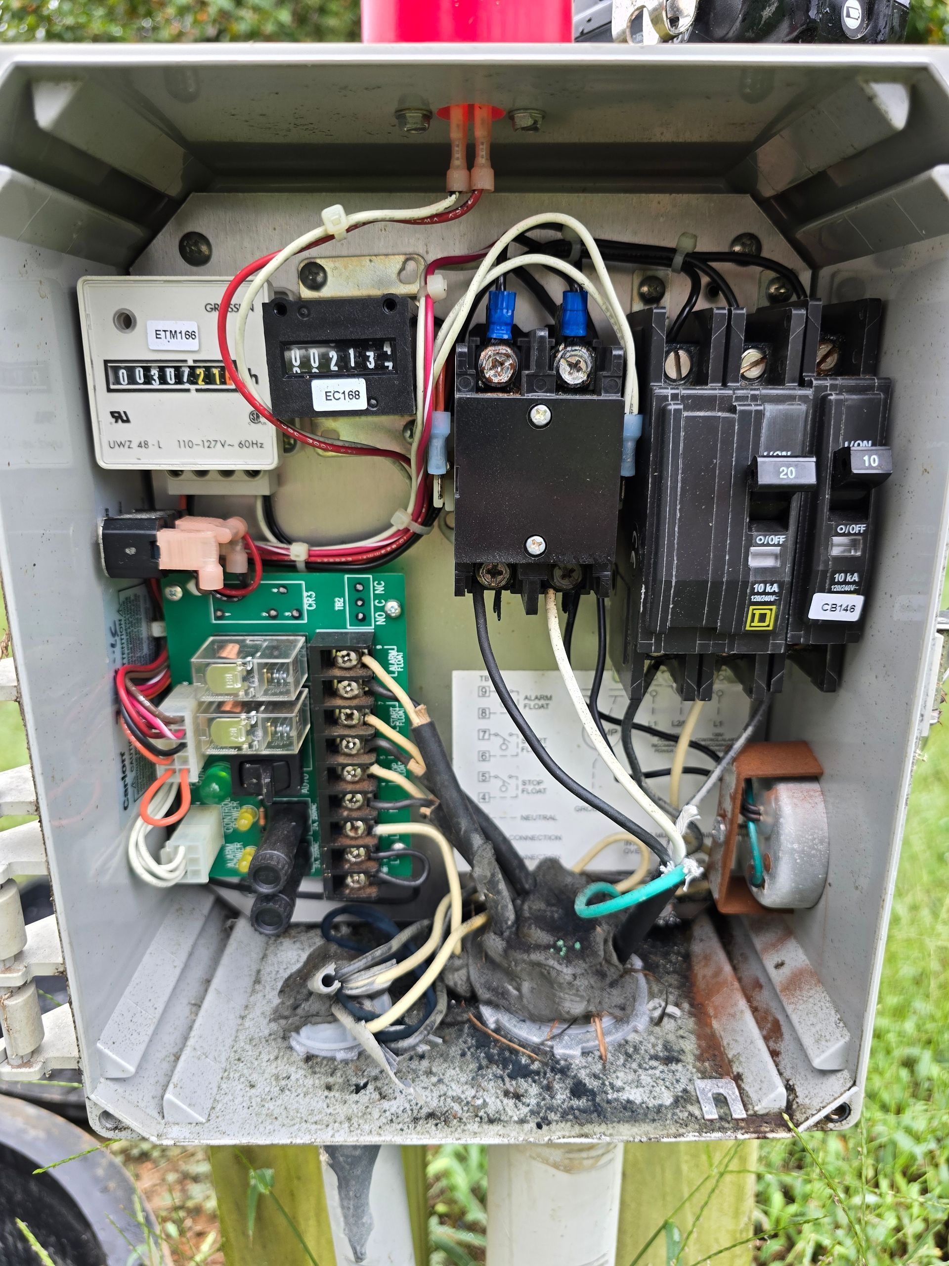 Open electrical control box with wiring, breakers, and meter, likely for a pump or similar system.