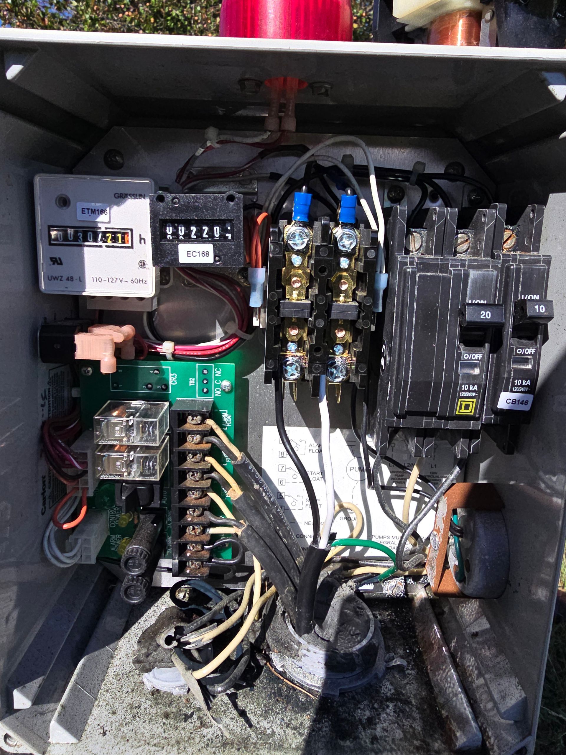 Open electrical panel with various components, including breakers, wires, and timers.