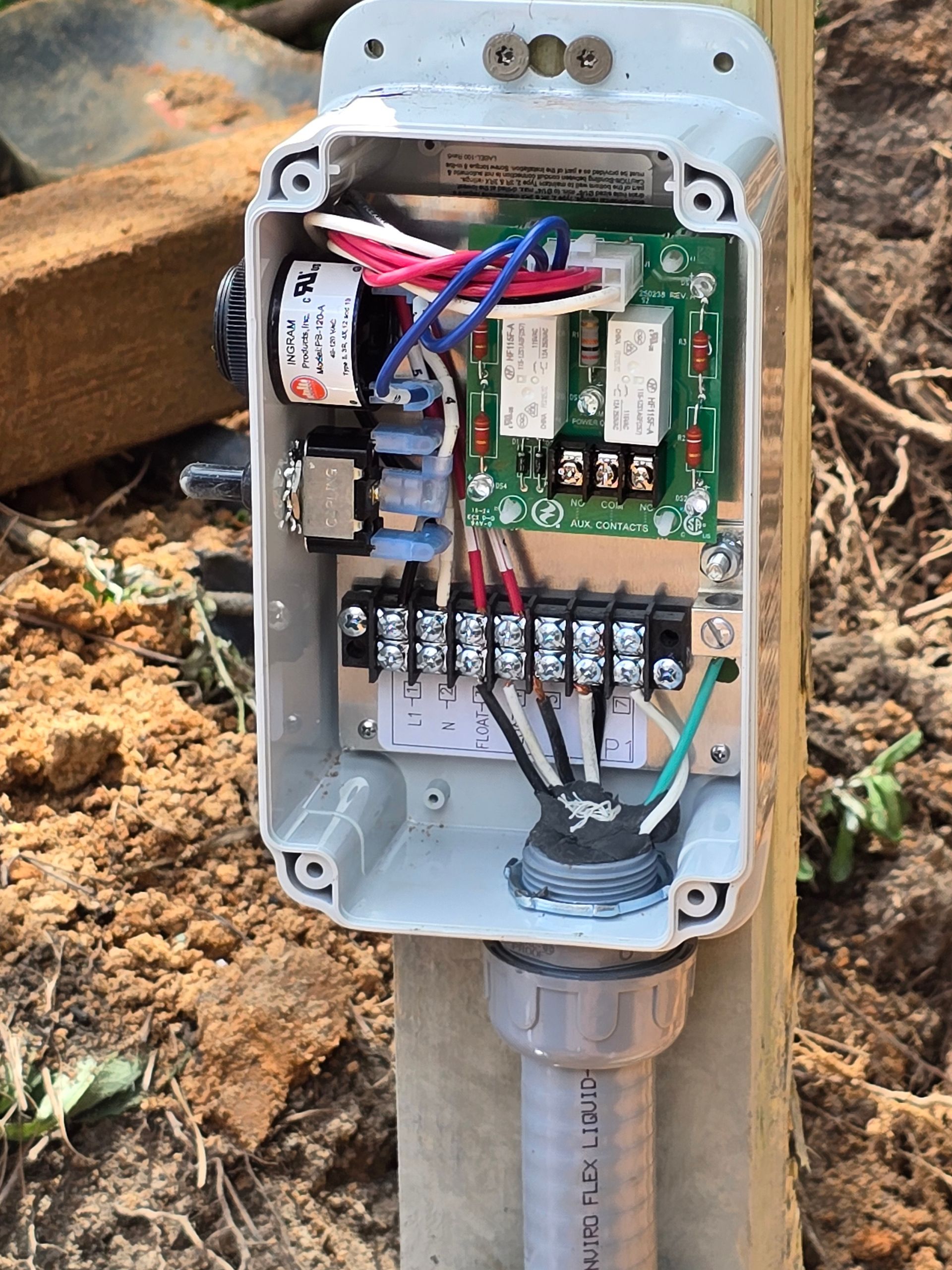 Open outdoor electrical control box mounted on wooden post. Wires and circuits visible inside.