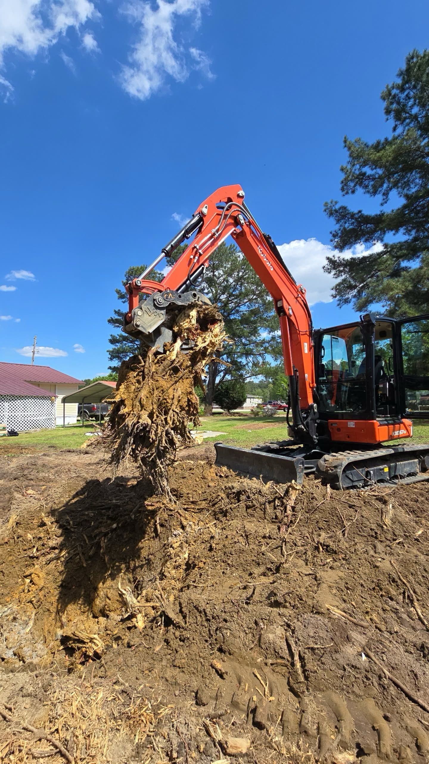 Orange excavator digging in a dirt pit on a sunny day.