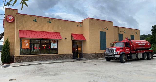 Red tanker truck parked outside a tan-colored restaurant with a red awning.
