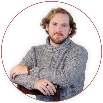 Portrait of a person in a gray sweater, seated with folded arms against a white background.