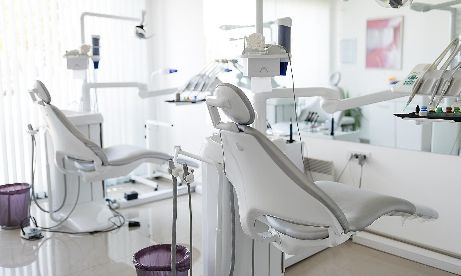 Bright dental clinic with white chairs, equipment, and large window light