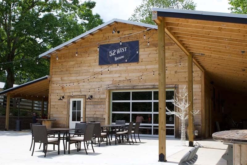 Wood-sided brewery with outdoor patio seating and a black sign reading “52 North”