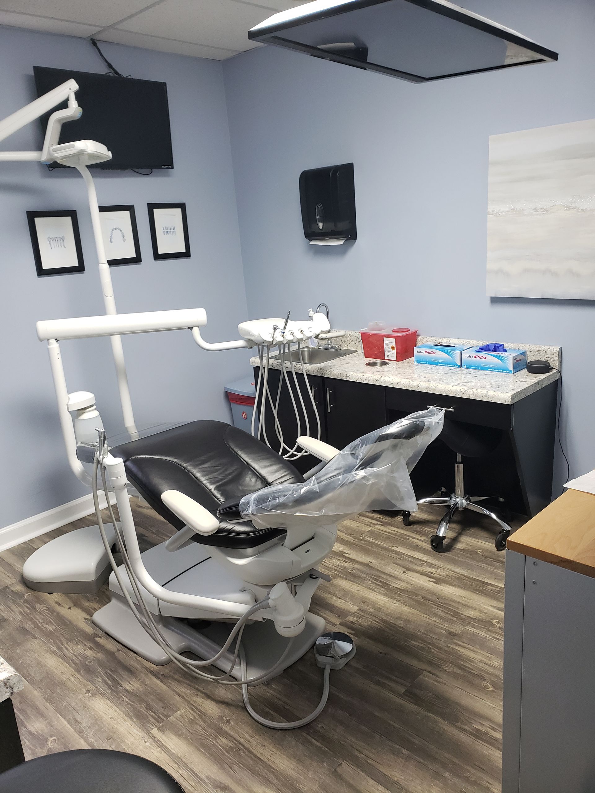 Dental exam room with chair, overhead light, sink, and supplies on a counter