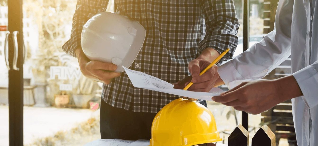 People reviewing building plans with a yellow hard hat on a construction site