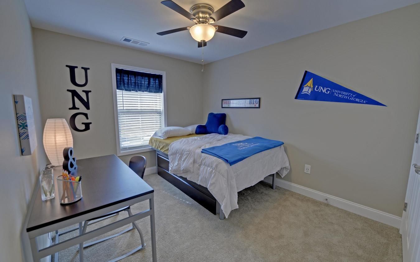 Bedroom with twin bed, blue accents, desk, and wall decor in a beige room