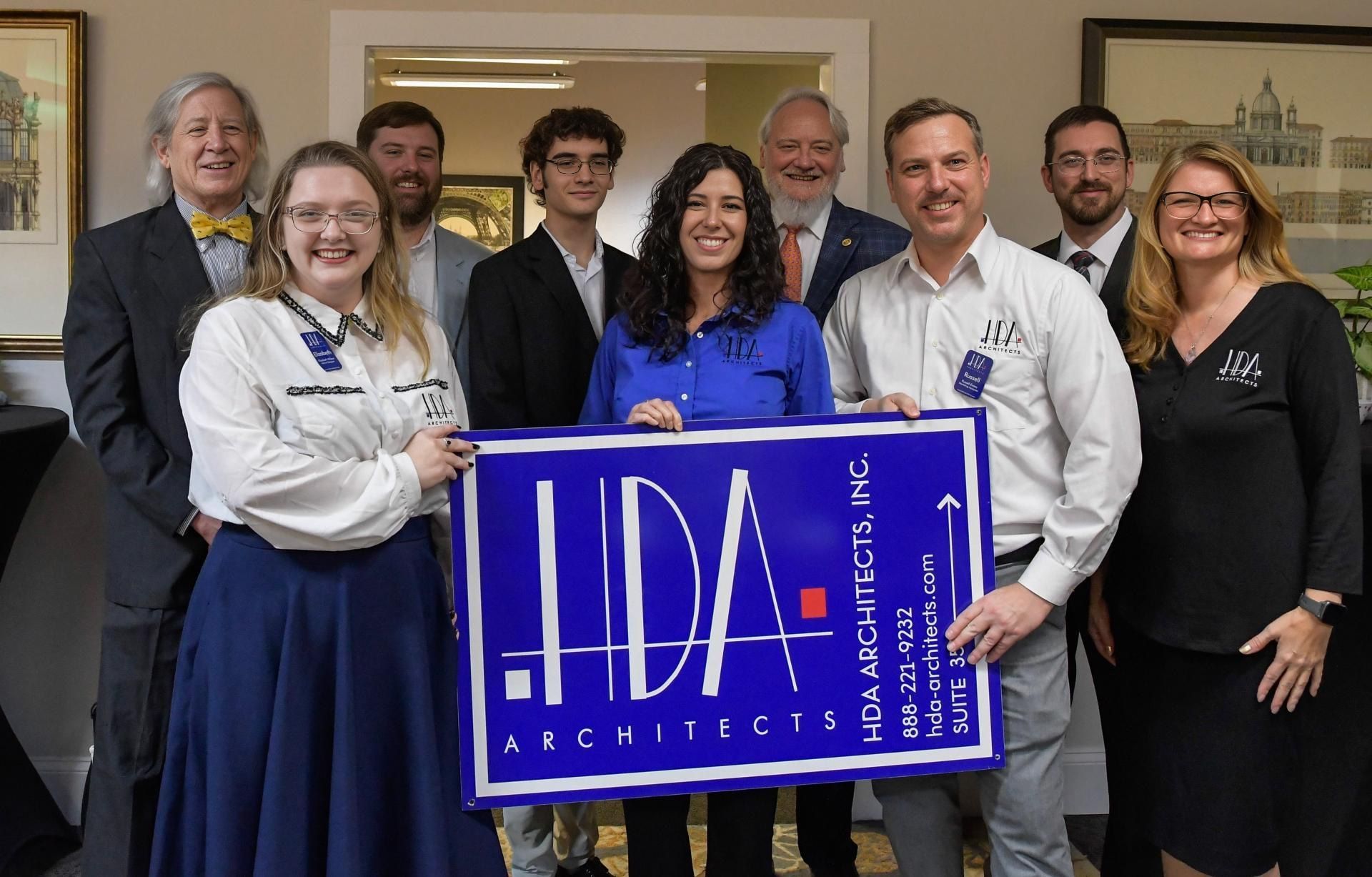 Group of smiling professionals holding a blue TechCivic sign indoors