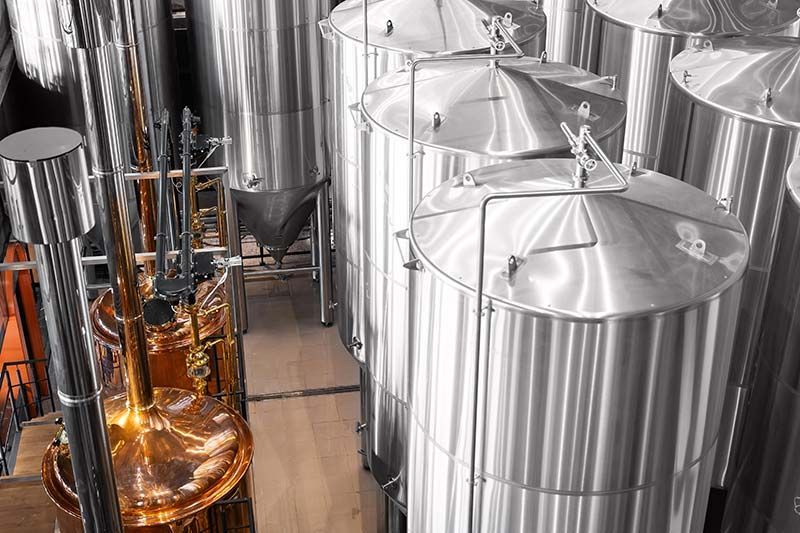 Stainless steel brewing tanks and copper pipes in an industrial brewery cellar