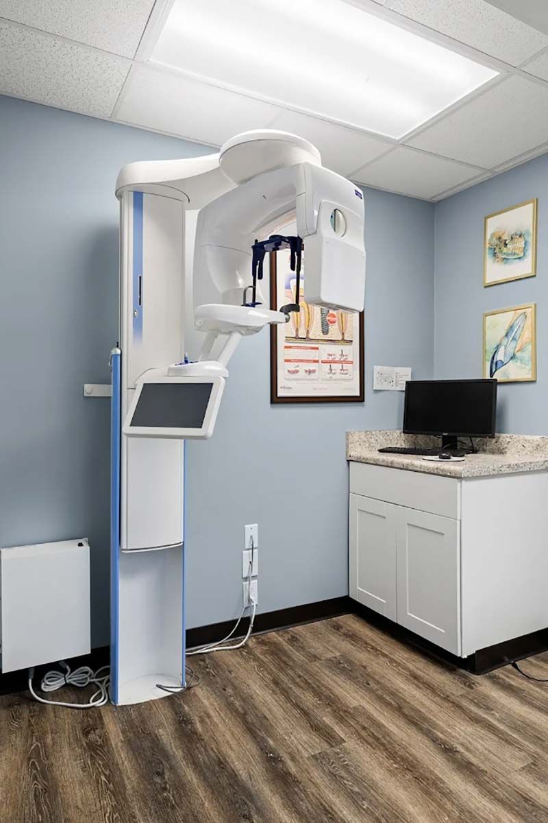 Dental X-ray room with panoramic scanner, monitor, and cabinets in a clean clinic interior