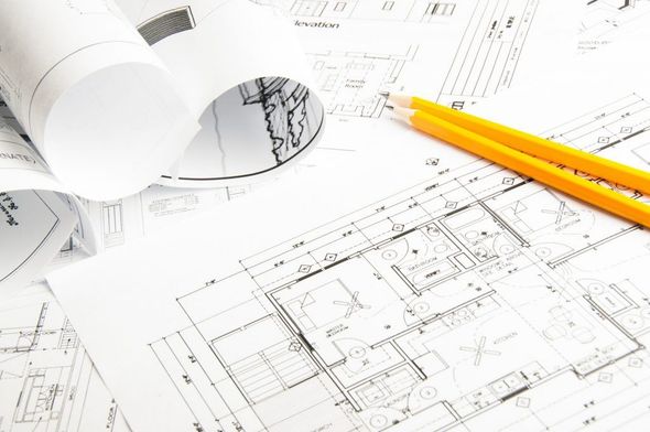 Rolled blueprints with yellow pencils on an architectural plan drawing