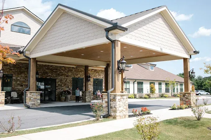 Covered hotel entrance with stone columns, beige roof, and driveway under a clear sky