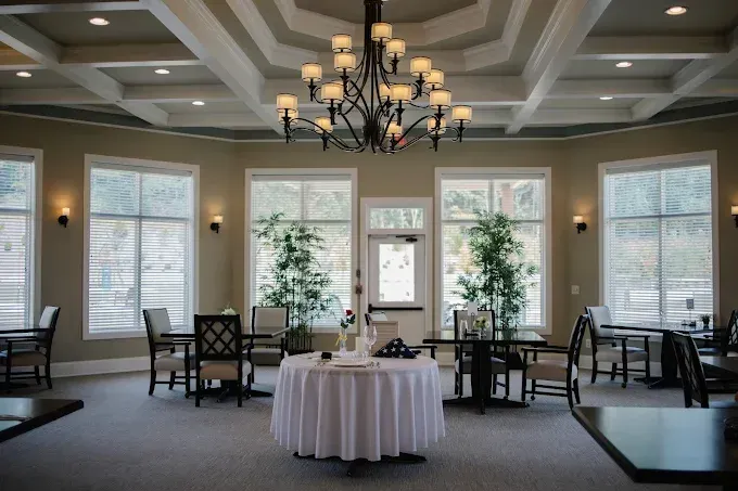 Elegant event room with chandeliers, round table centerpiece, and large windows with blinds