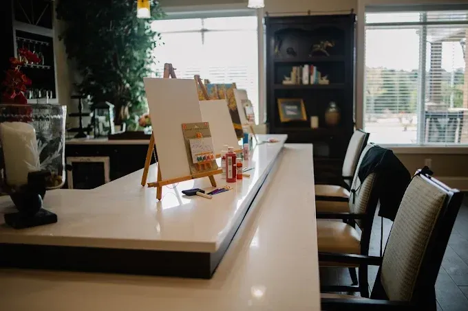 Modern kitchen island with chairs, easel, and sunlight from large windows