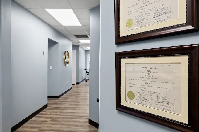 Hallway with framed certificates on a light blue wall and wood flooring