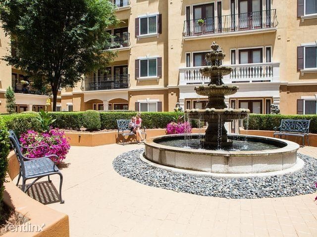 Courtyard with a tiered fountain, pink flowers, benches, and apartment balconies in the background