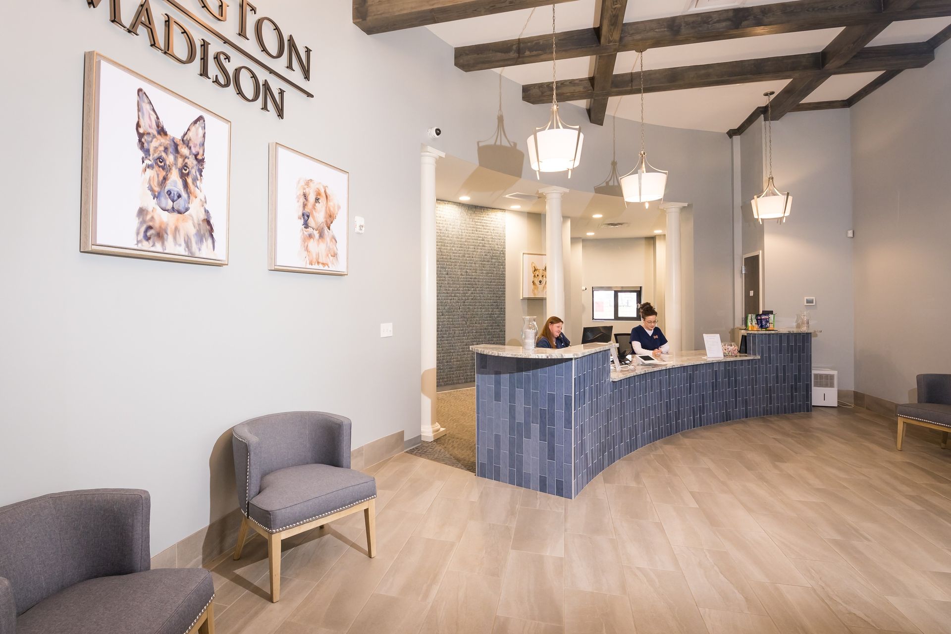 Modern office lobby with reception desk, gray chairs, wall art, and wood floors