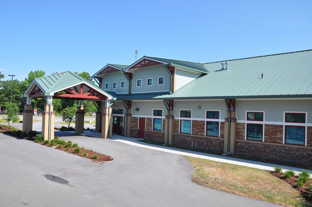 Full exterior view of Wayne Veterinary Clinic with green metal roof, covered entrance, and parking area