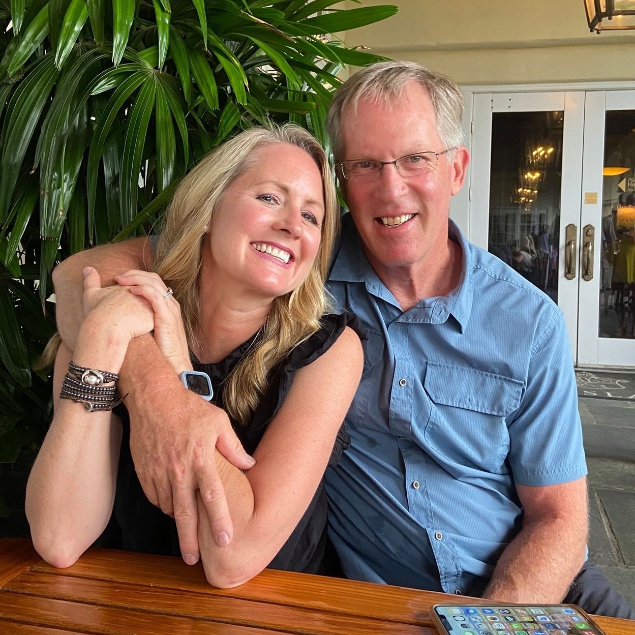 A man and a woman are posing for a picture while sitting at a table.