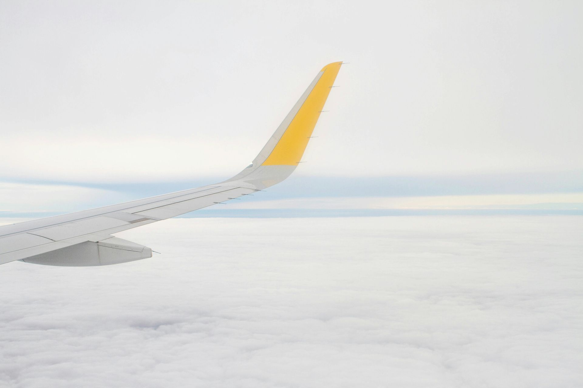 The wing of an airplane is flying through the clouds.