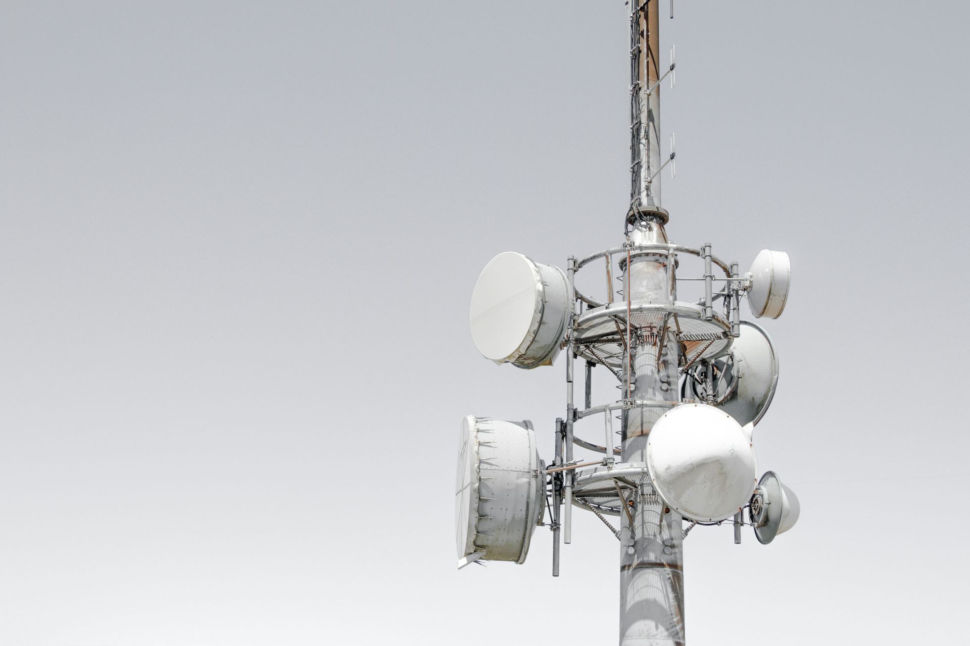 A telephone tower with a lot of antennas on it against a cloudy sky.