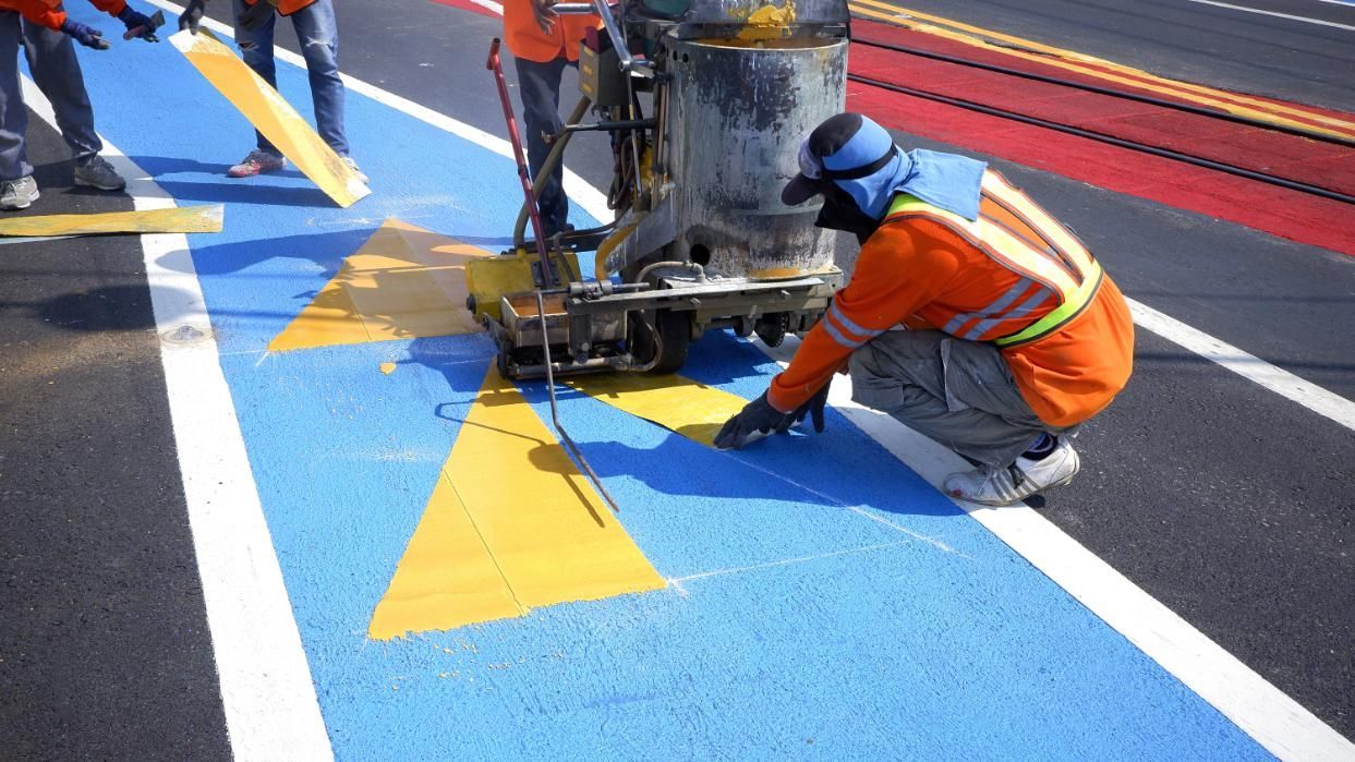A Man is Kneeling Down While Painting a Road With a Machine — North Coast Line Marking in Yamba, NSW