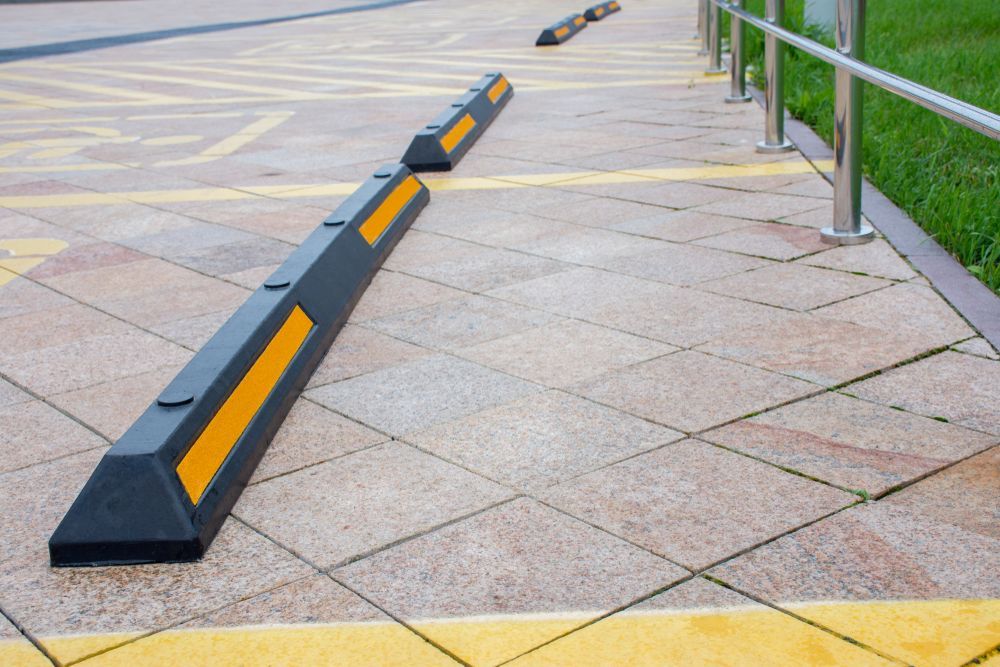 A Row of Black and Yellow Parking Blocks on a Sidewalk — North Coast Line Marking in Port Macquarie, NSW