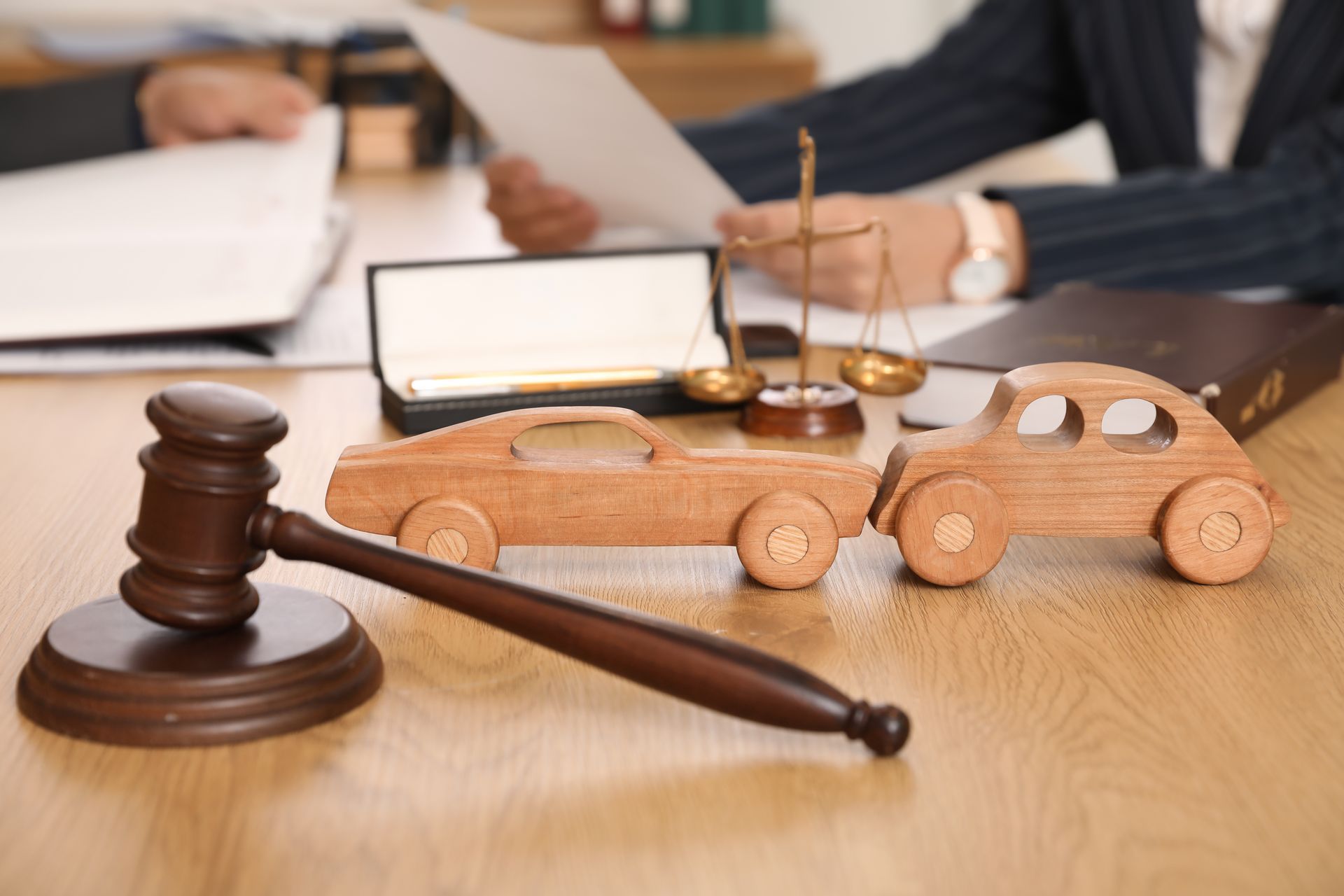 Close-up of wooden cars with a judge's gavel on a car lawyer's table during a meeting in an office.