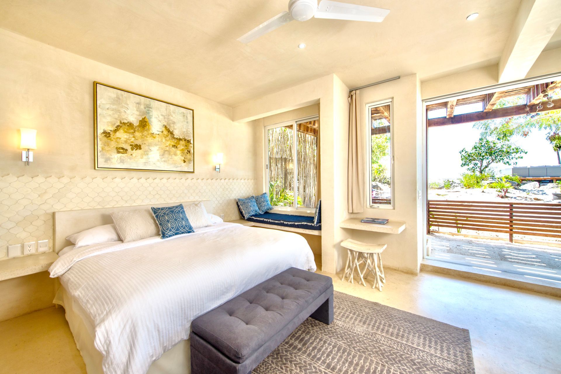 Bedroom with king bed, window seat, and open door to outside patio.