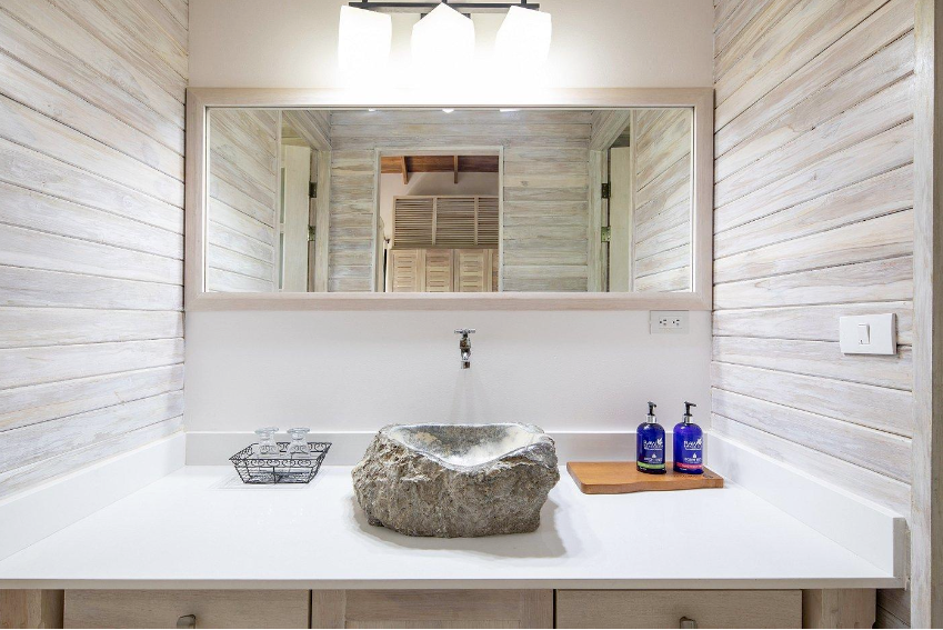 A bathroom with a large mirror and a stone sink