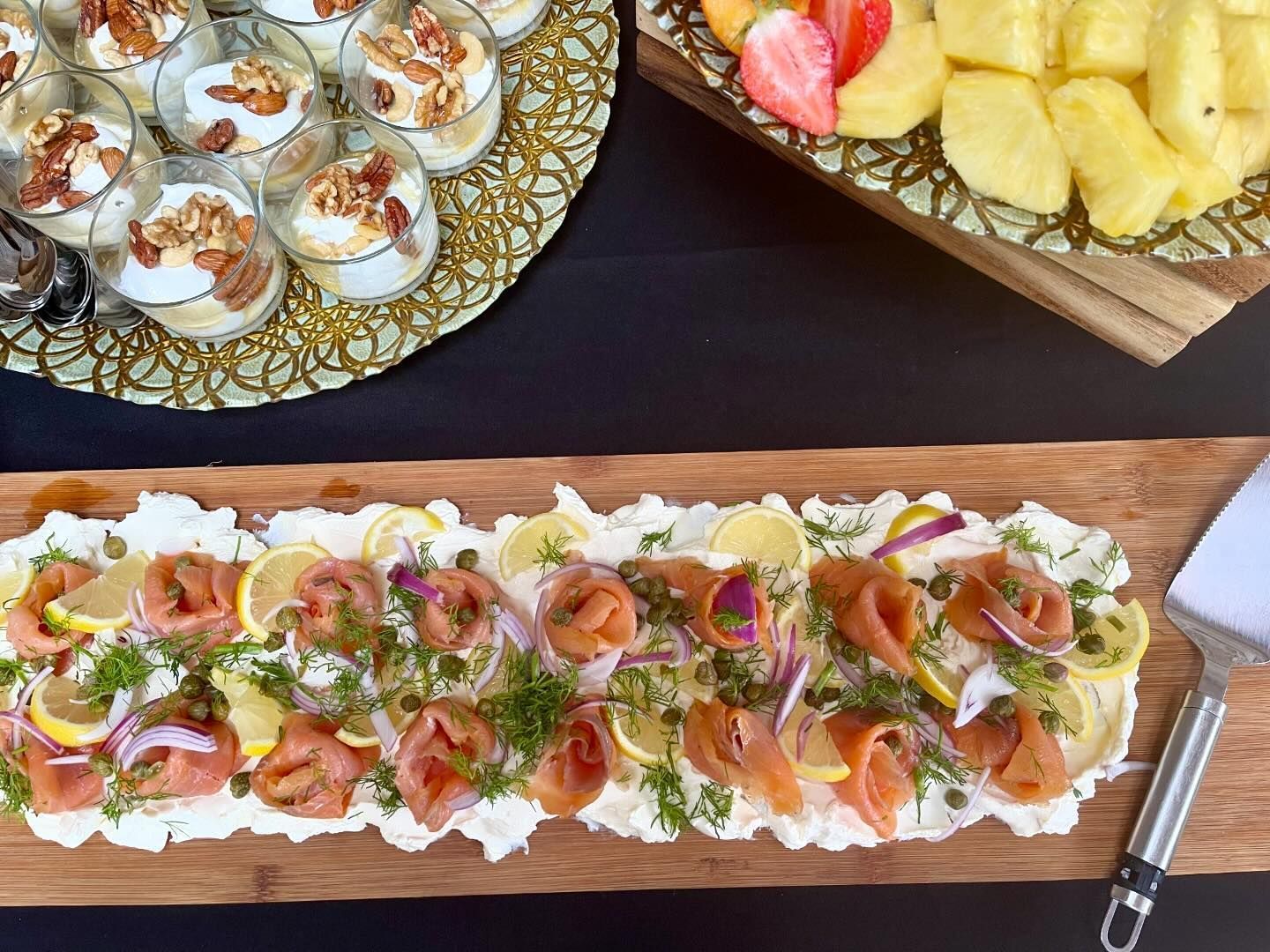 A wooden cutting board topped with food and a spatula on a table.