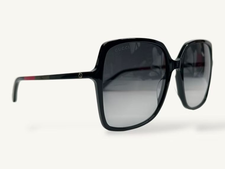 Occhiali da sole neri oversize dalla forma squadrata con lenti scure sfumate su sfondo bianco.