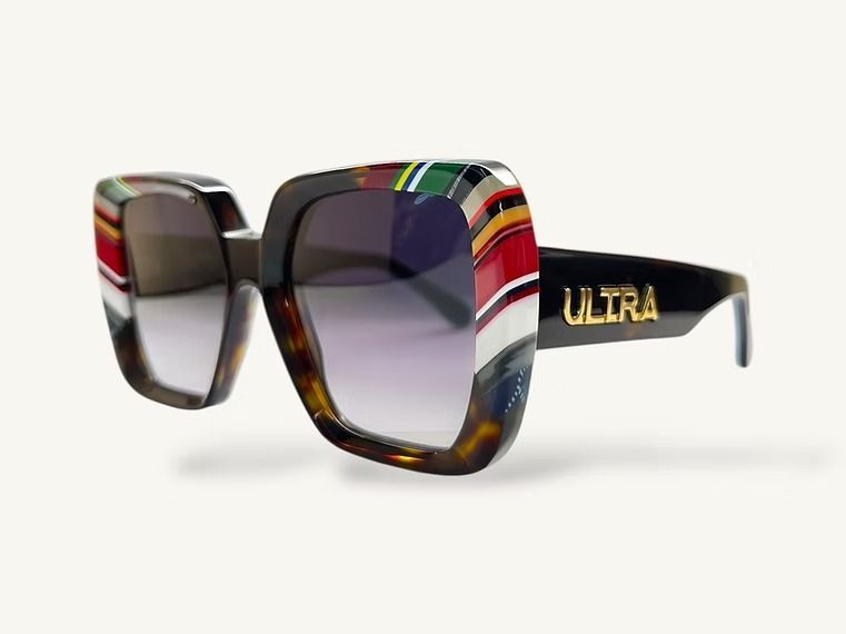 Occhiali da sole oversize a righe colorate con lenti scure e aste nere su sfondo bianco.