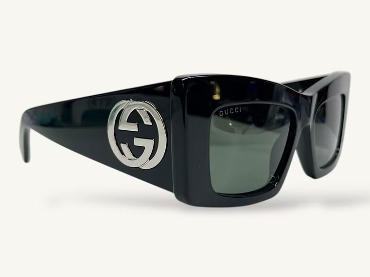 Occhiali da sole Gucci neri con grande logo sull'asta, mostrati su sfondo bianco.