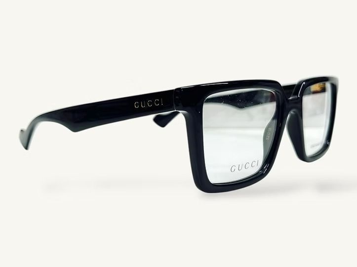 Occhiali da vista Gucci rettangolari neri con lenti trasparenti su sfondo bianco.