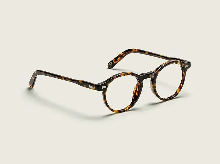 Occhiali da vista tartarugati con lenti rotonde su sfondo beige chiaro