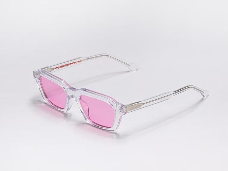 Occhiali da vista con montatura trasparente e lenti rosa su sfondo bianco.