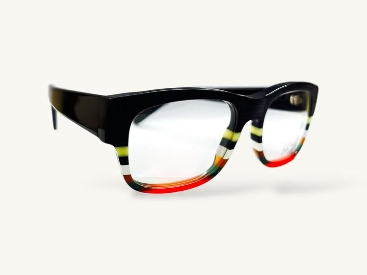Occhiali neri con montatura a righe multicolori su sfondo bianco.