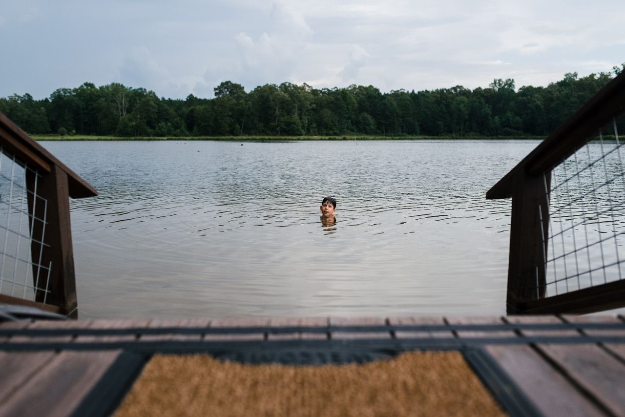 A person is swimming in a lake from a dock