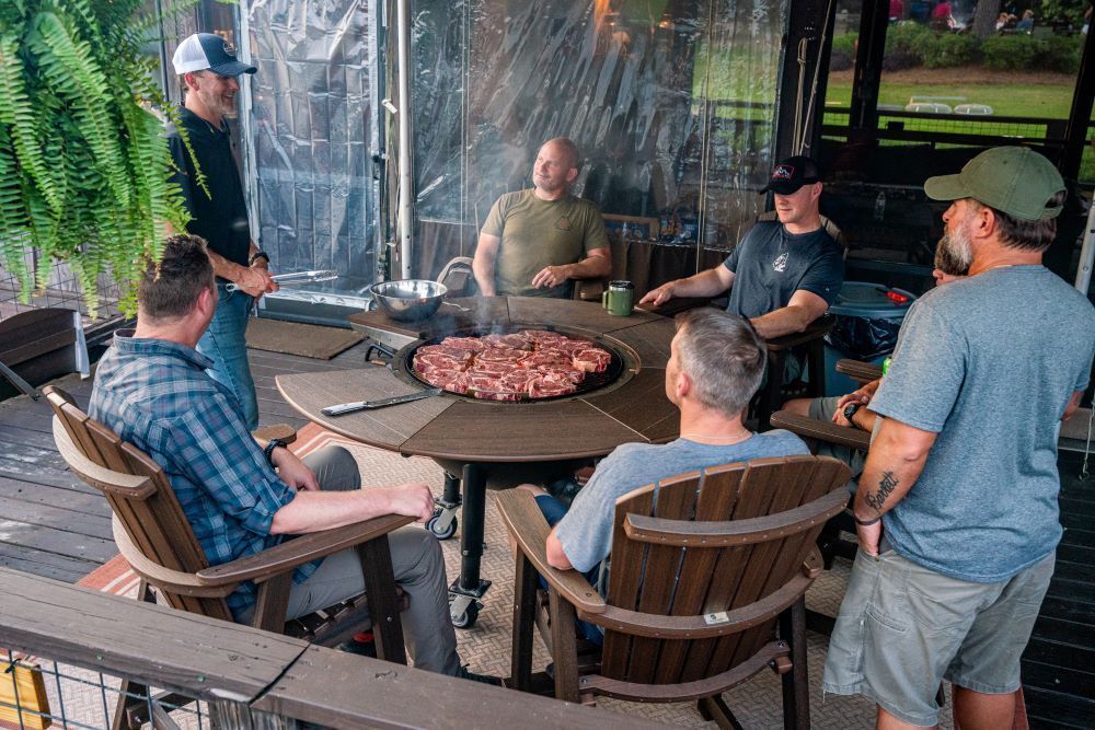 A group of men are sitting around a table with a pizza on it.