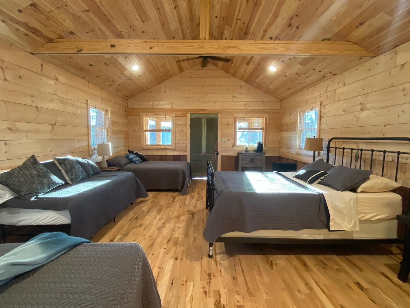 A large wooden cabin with four beds and a couch.