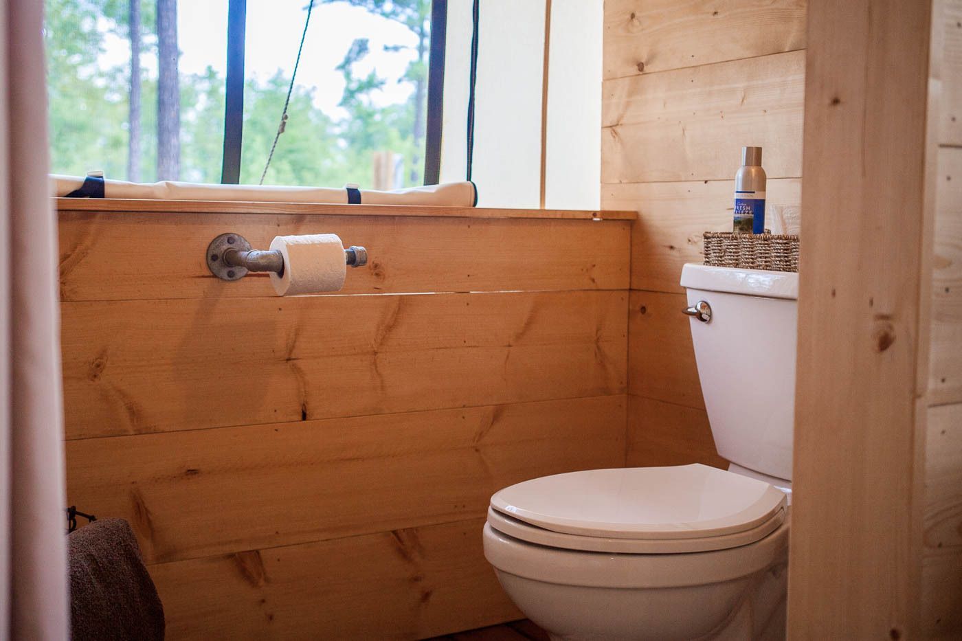 A toilet is sitting in a bathroom next to a window.