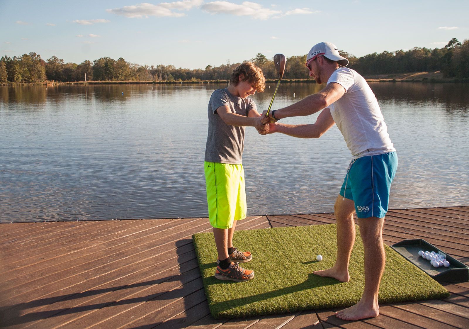 A man is teaching a young boy how to play golf.