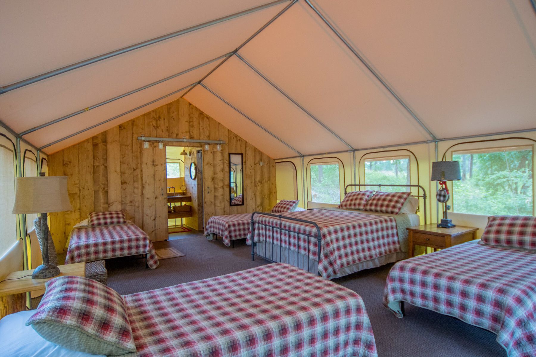 A large tent with four beds in it.