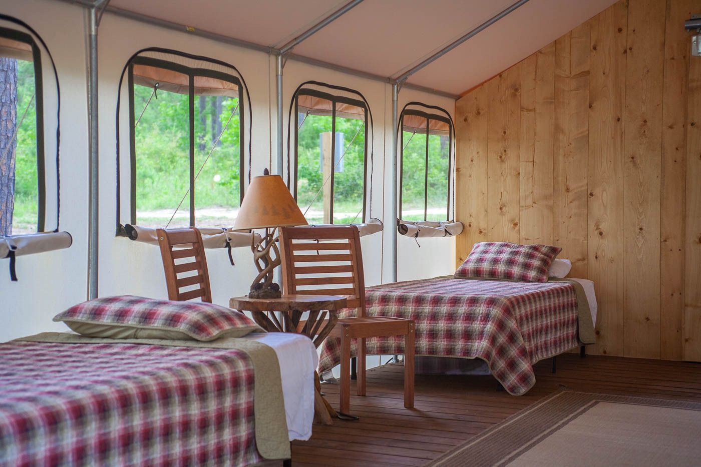 A room with two beds , a table and a lamp.