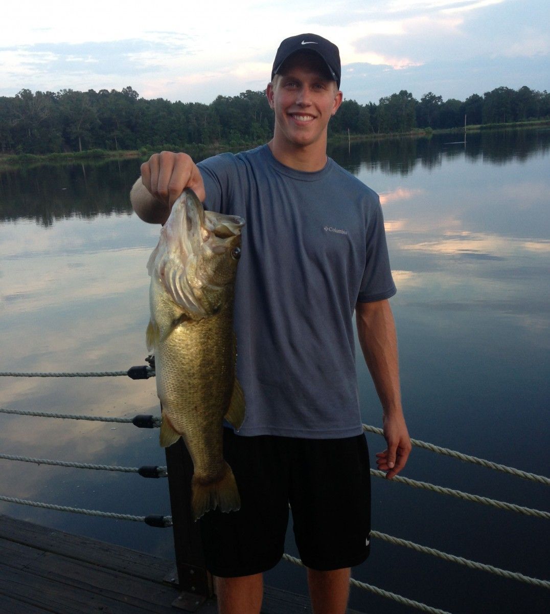 A man is holding a large fish in front of a body of water