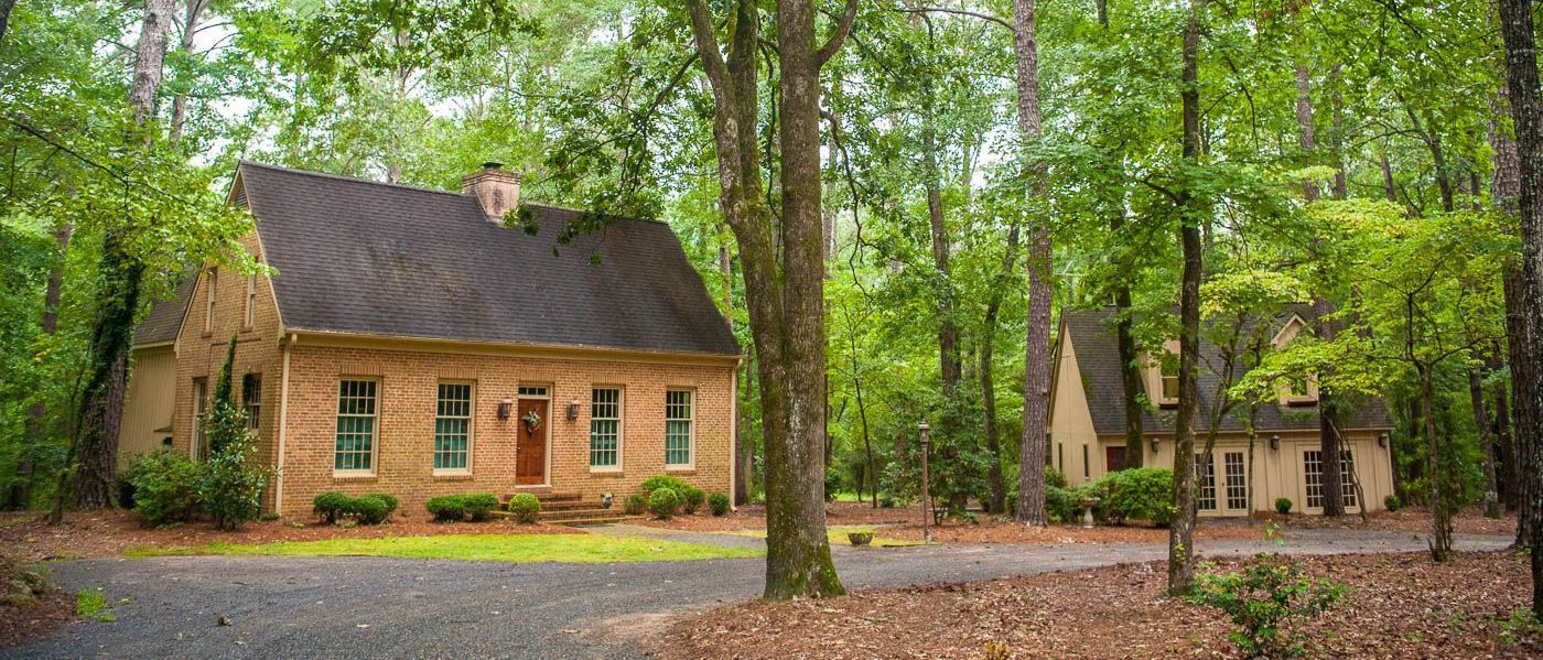 A wooden house is surrounded by trees in the middle of a forest.