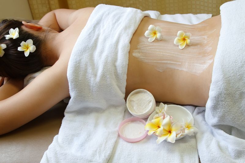 Person receiving spa treatment with flowers and cream on their back.